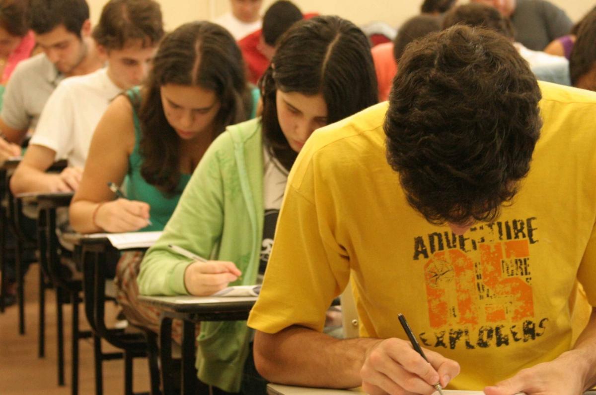 Estudantes adolescentes curvados sobre mesas fazendo provas