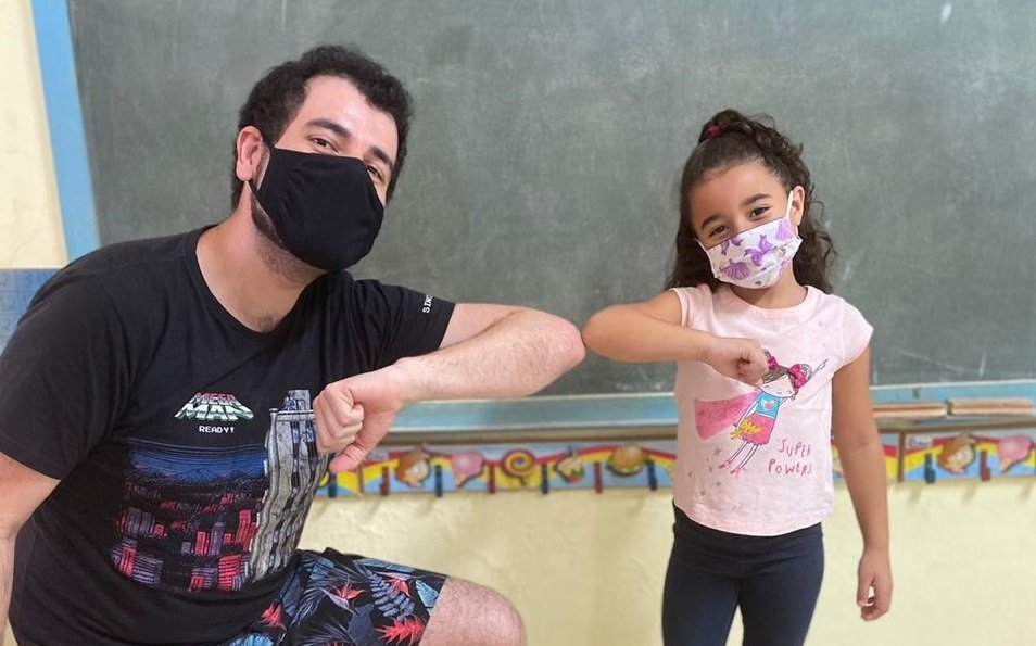 professor evandro tortora cumprimento uma das crianças da sua turma com o cotovelo, conforme manda os protocolos de segurança da covid-19
