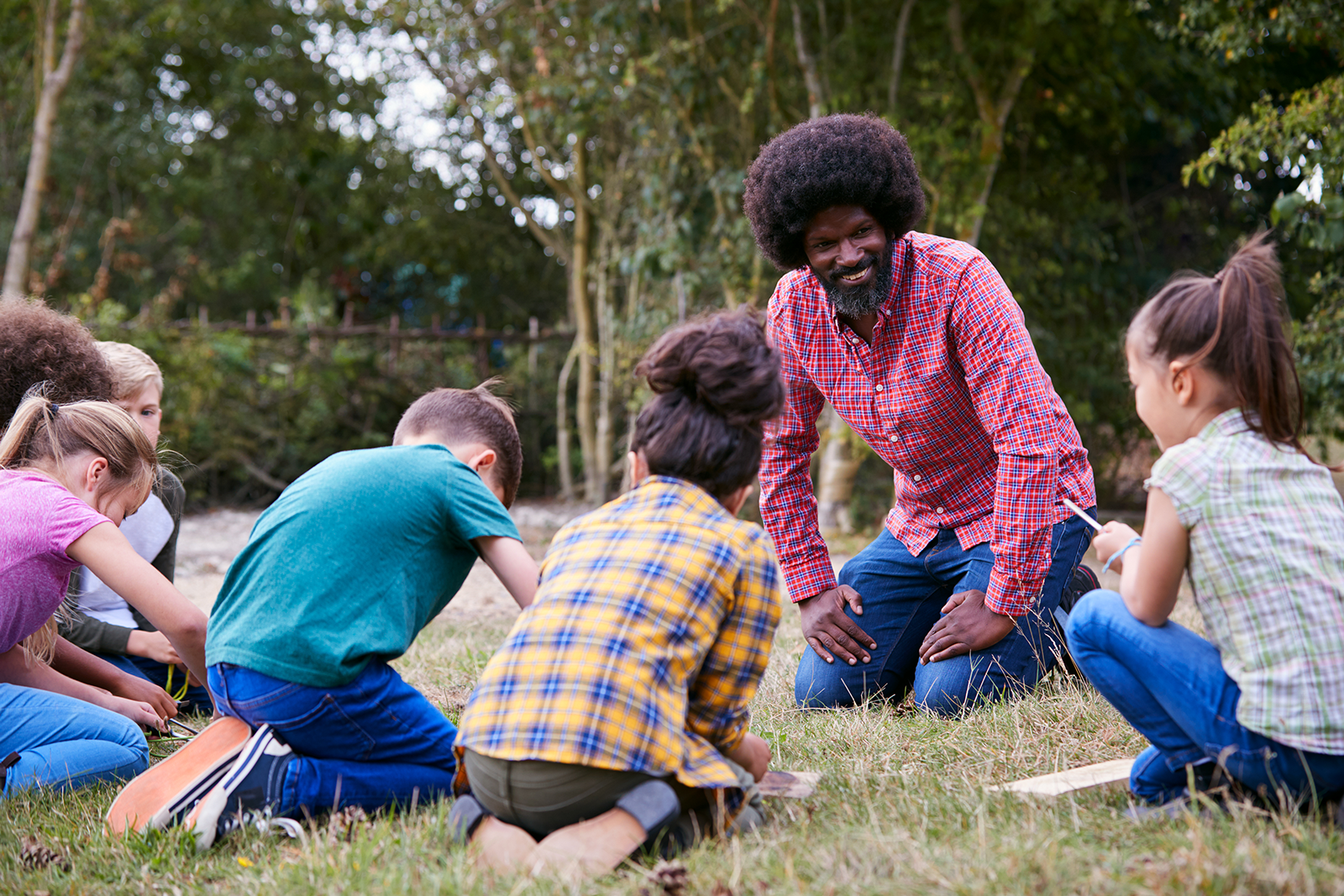 Professor e alunos em atividade externa em um parque.