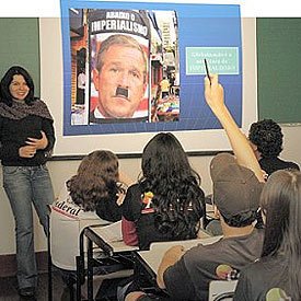 Luciana projeta para a turma a montagem em que Bush usa bigode de Hitler e a charge animada: humor e imperialismo. Foto: Valter de Paula