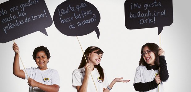 Alunos seguram placas com frases sobre o verbo gustar nas aulas de espanhol. Foto: Patricia Stavis