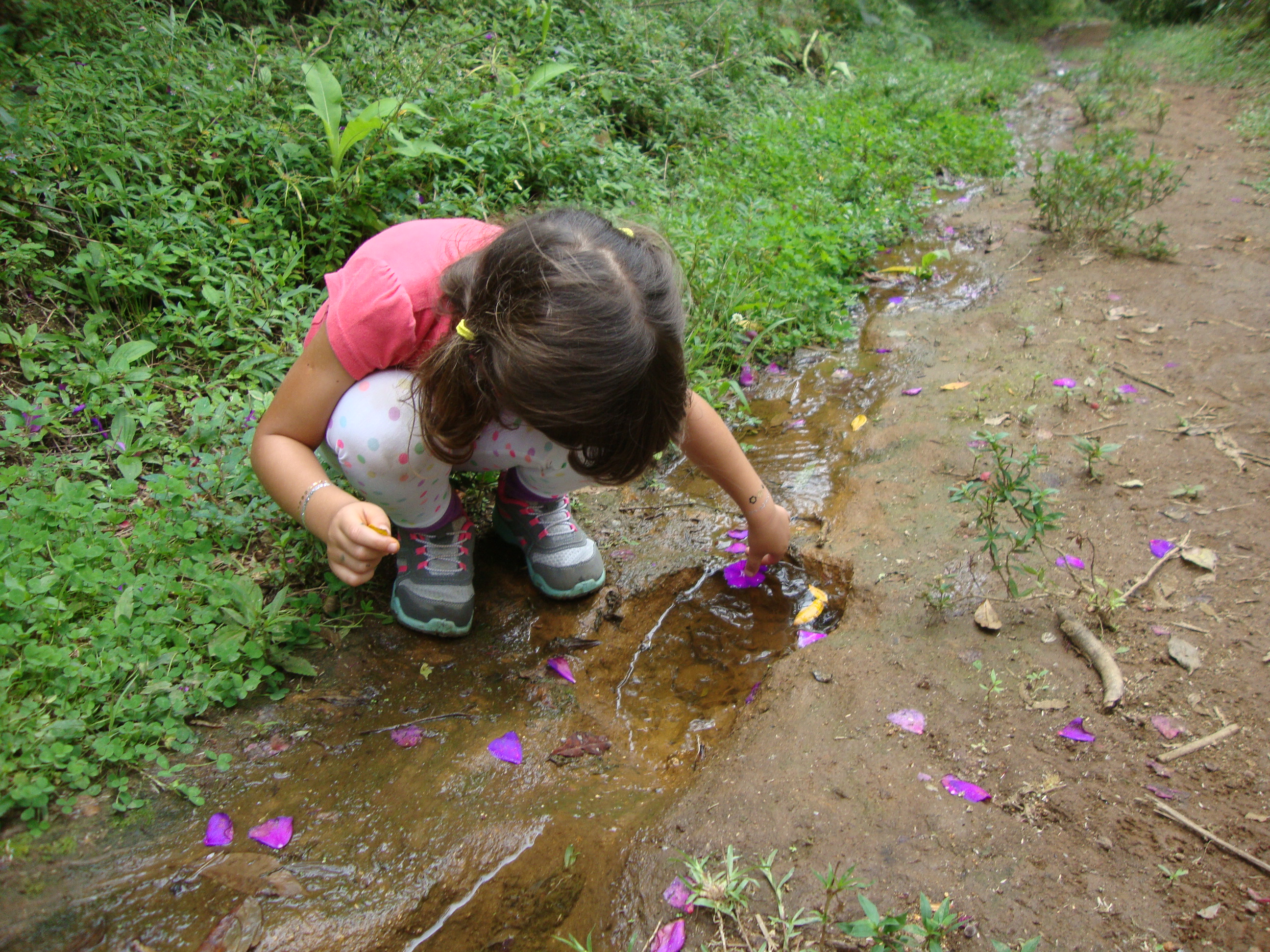 Criança brincando com pétalas de flores em ambiente natural