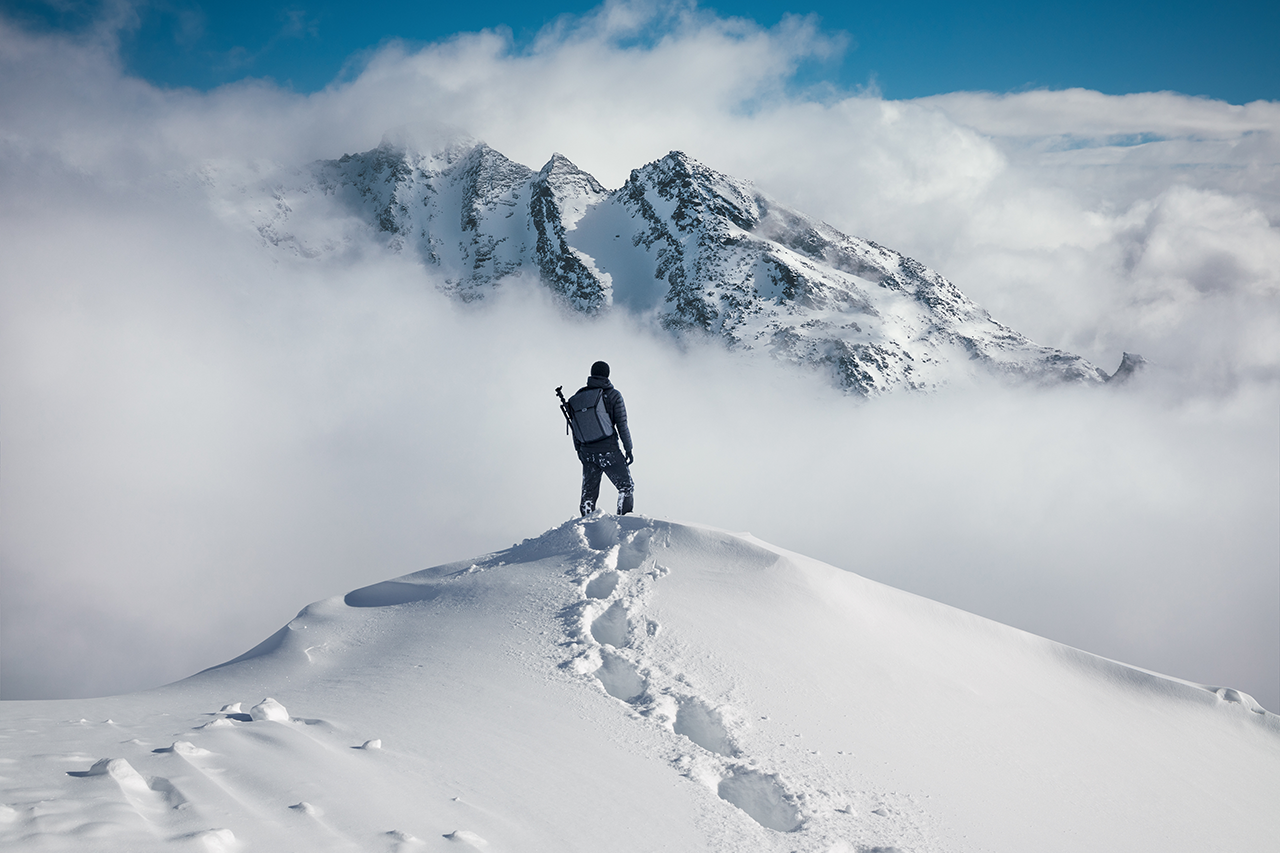 Fotografia de montanhista em topo nevado.