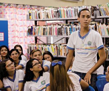 Garoto de pé em meio aos colegas durante avaliação de desempenho da escola