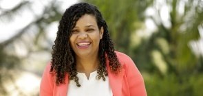 Uma mulher negra de cerca de 35 anos sorrindo