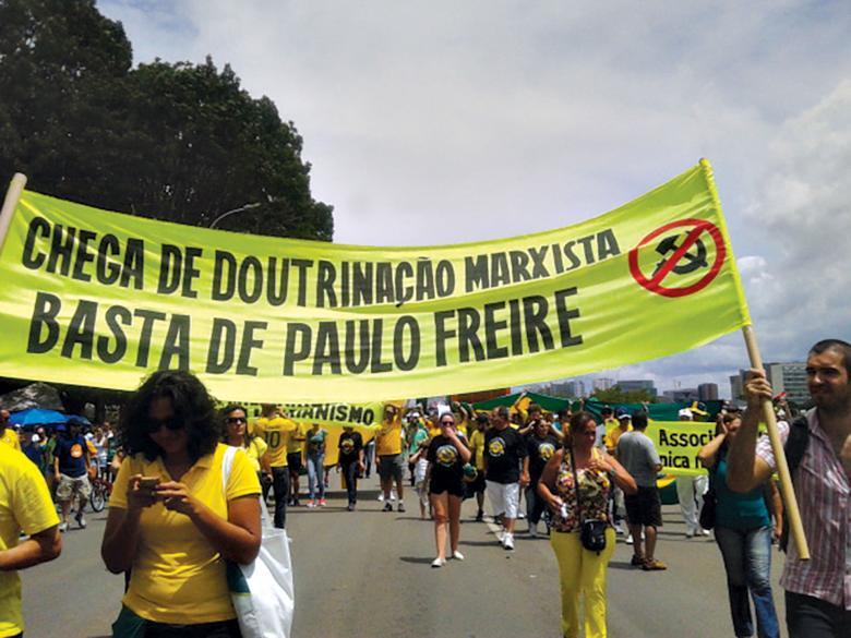 Manifestantes carregam faixa com cítica ao marxismo e Paulo Freire