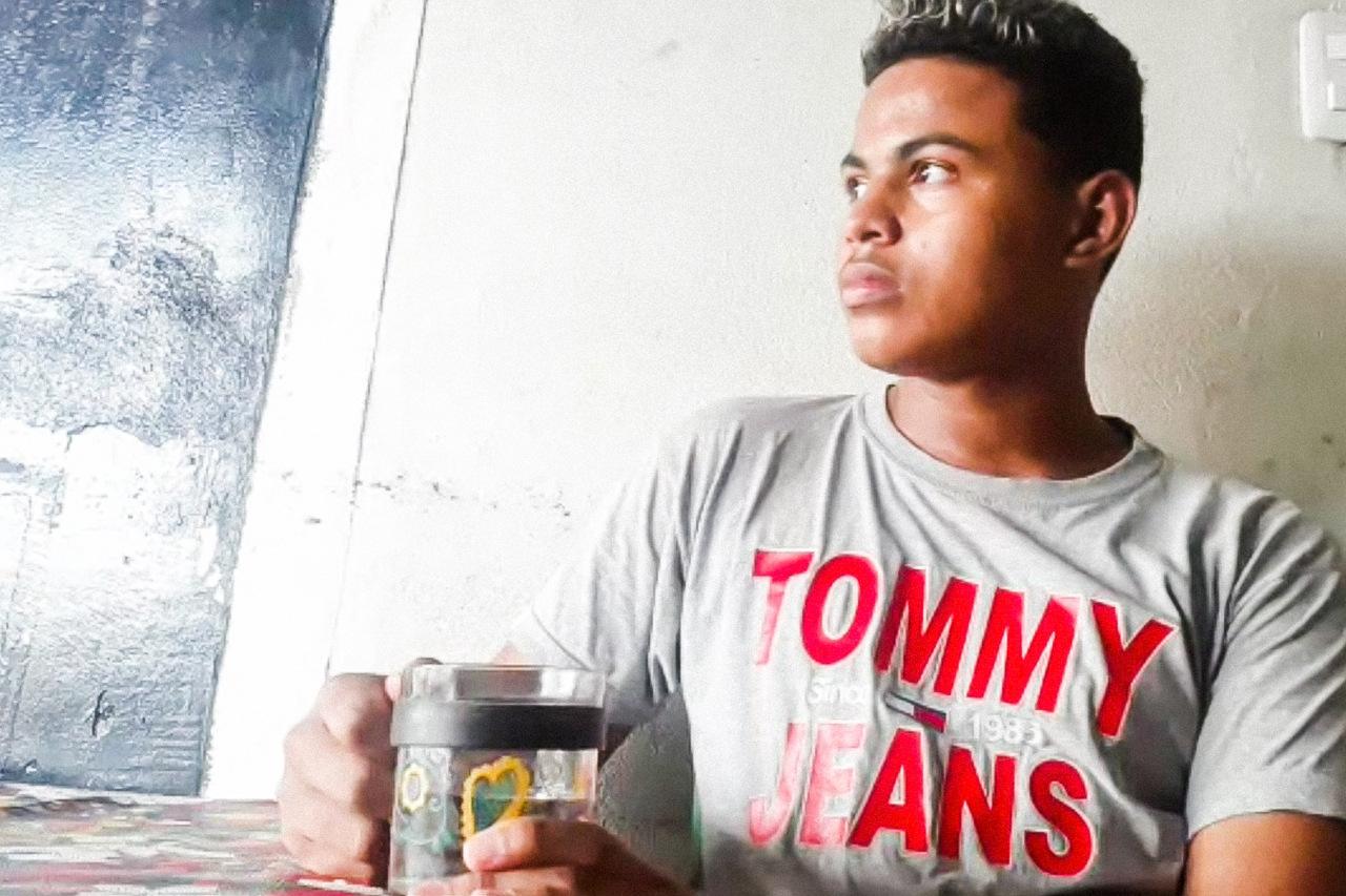 Fotografia feita remotamente via google duo do aluno Wallisson Marinho, estudante do 3º ano do ensino médio na rede estadual do maranhão. Wallisson está sentado na mesa tomando café.