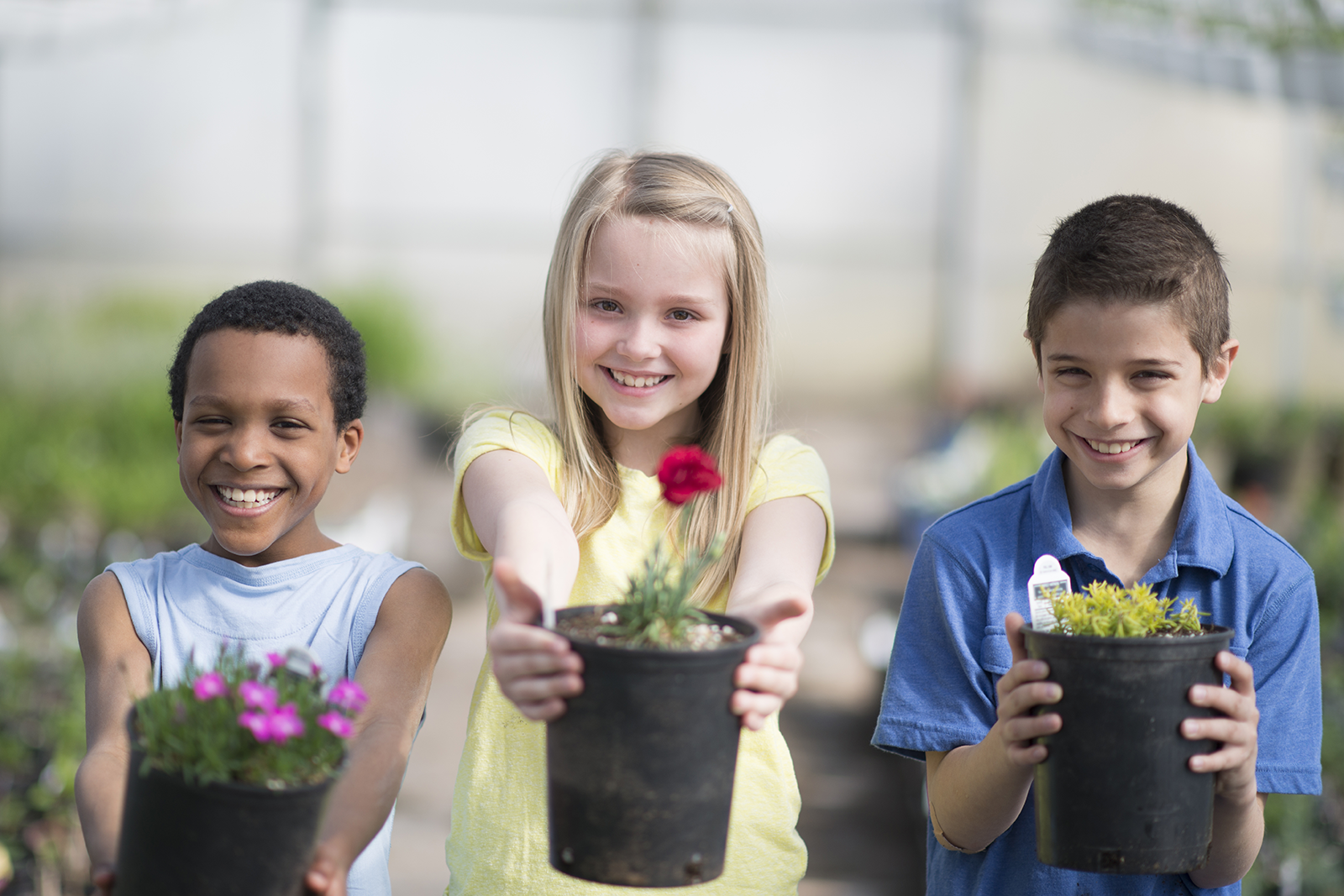 Alunos segurando vasos com flores