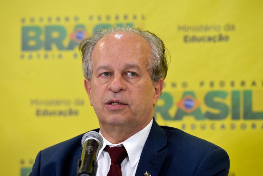 Renato Janine Ribeiro em pronunciamento sobre Enem 2015 diante de um pôster com o slogan "Brasil Pátria Educadora"