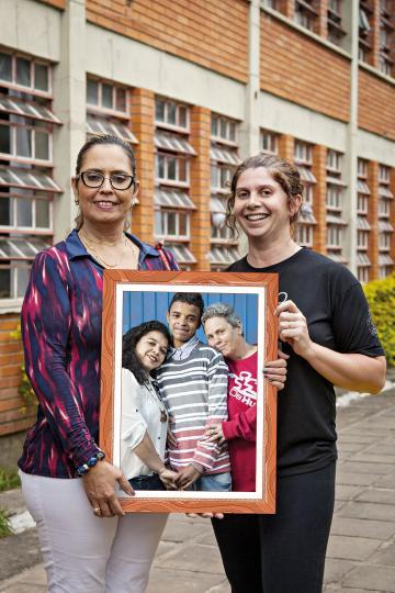 Diretora e vice-diretora da escola de Porto Alegre seguram um quadro com uma foto de uma família formada por duas mulheres e um garoto